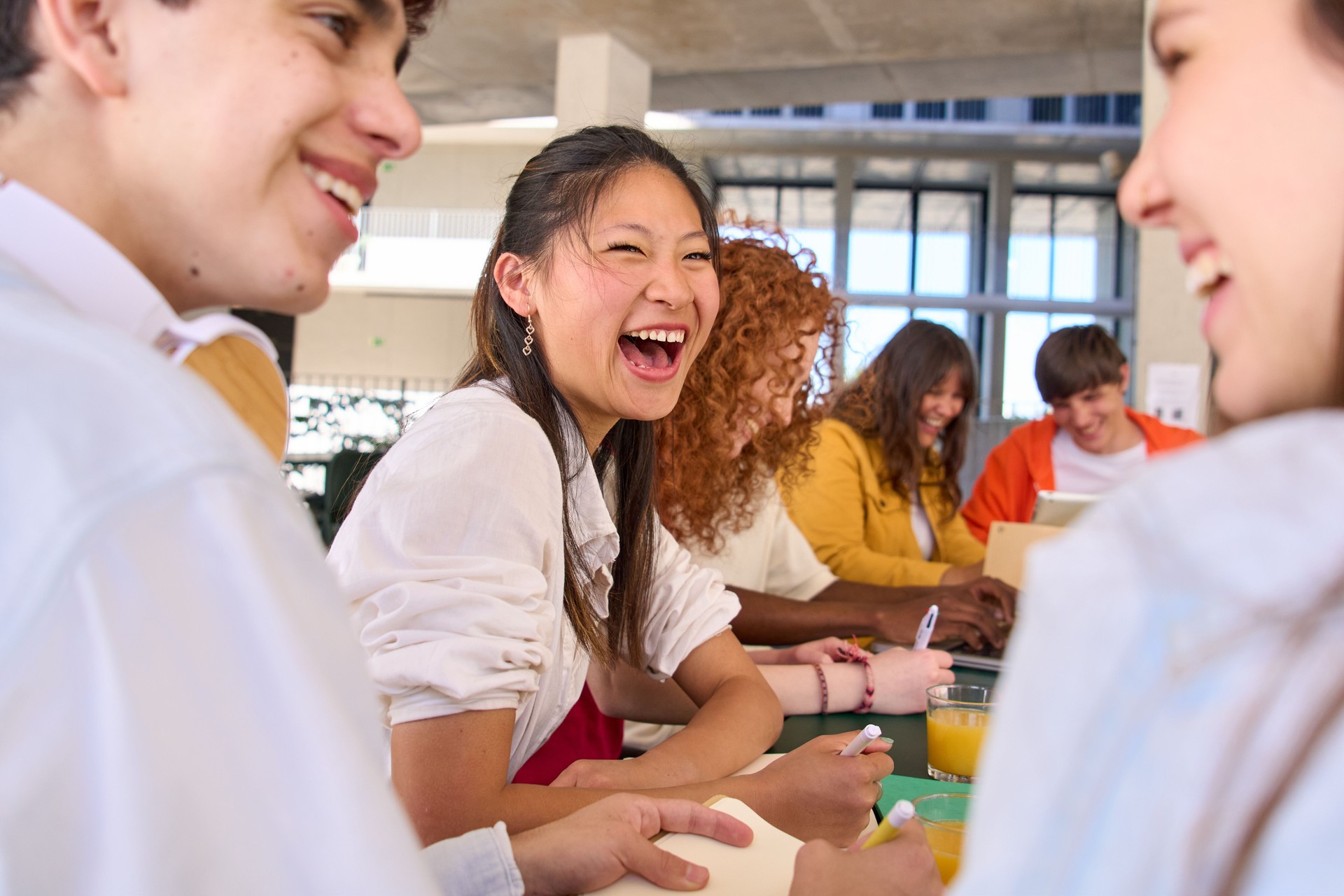 Group of smiling young Caucasian students talking while studying in university campus cafeteria.